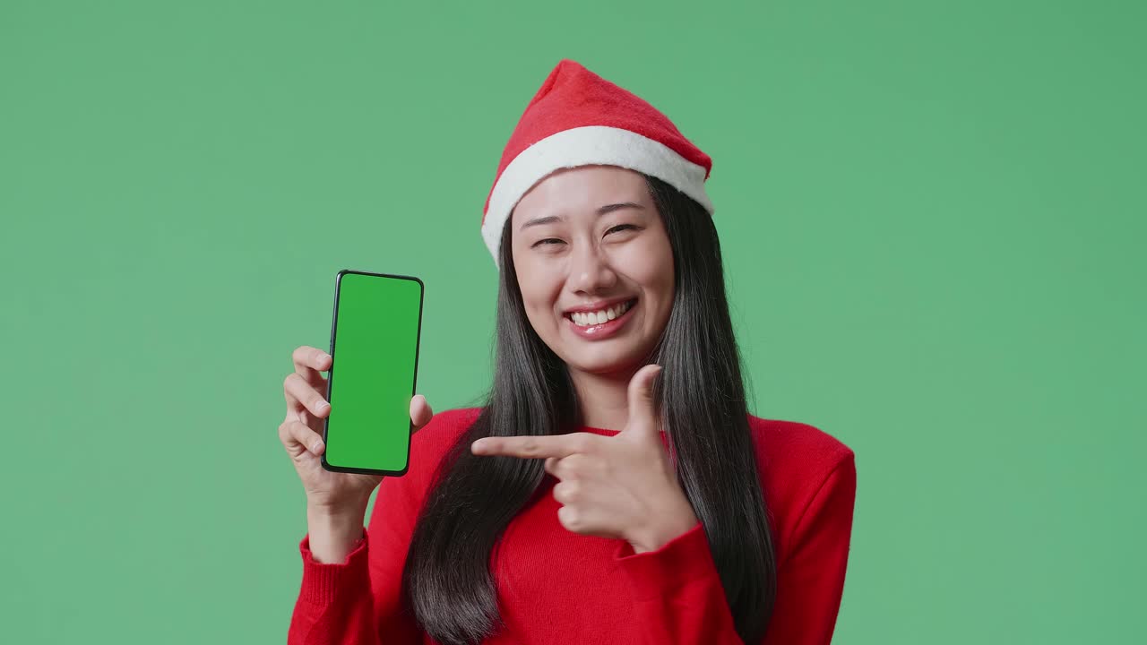 녹색 화면 을 가진 스마트폰 을 보여 주는 산타 모자 를 입은 여자