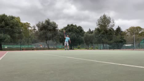 front view of active sporty male tennis player serving ball during match on hardcourt