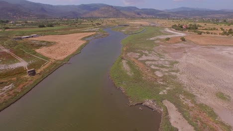 aerial: a river delta with a road-bridge passing through and some agricultural buildings