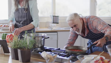 middle aged caucasian couple cooking in kitchen at home, slow motion