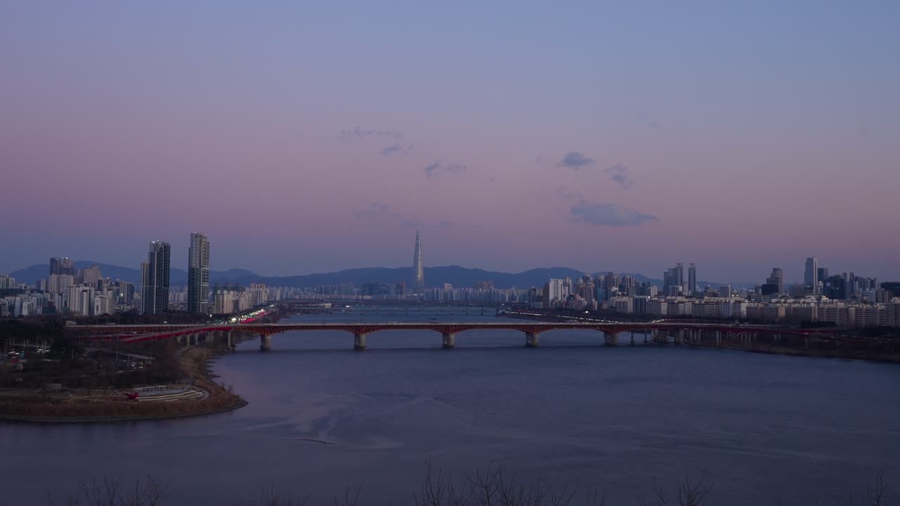 Splendida vista panoramica dello skyline di Seul al tramonto durante l'inverno, che mostra la Lotte World Tower e il ponte Seongsu sul fiume Han con cielo viola - timelapse dal Dal Maji Park