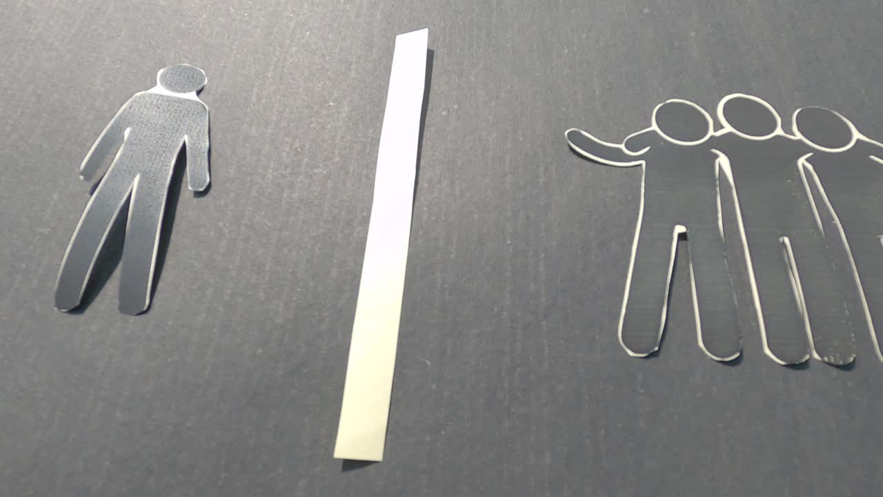 그룹에서 고립되어 서있는 종이 남자를 보여주는 종이. 외롭고 외롭다고 느다. 사회적 고립과 거부 개념을 설명하는 비디오.