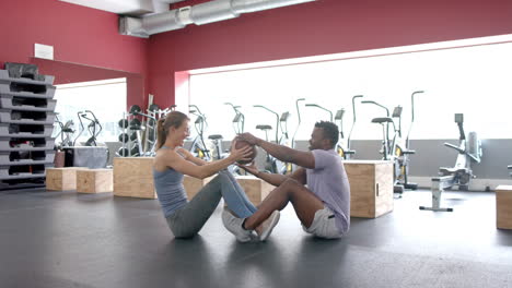 una joven blanca en forma y un hombre afroamericano haciendo ejercicio en el gimnasio.
