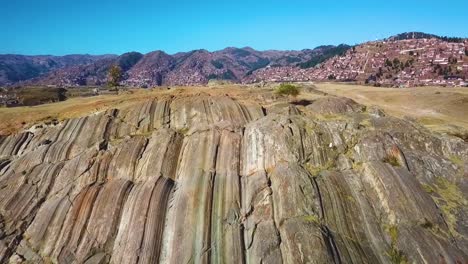 drone flying over natural rock slides and revealing incan ruins sacsayhuaman and cusco city