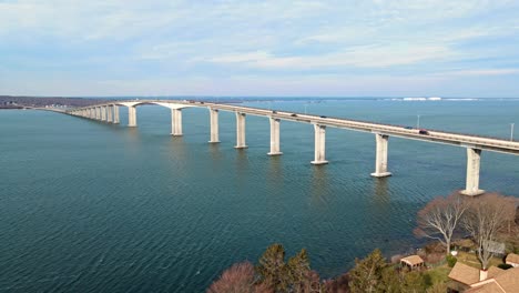 a slow aerial 4k shot of a bridge with cars on it and with water underneath the bridge with a blue sky overhead