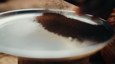 tamiz ugandés tradicional usado para tamizar café molido marrón oscuro en un plato grande