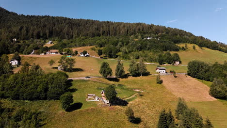 picturesque countryside with village on meadows and dense woodland in background during sunny day in orobie alps, northern italy