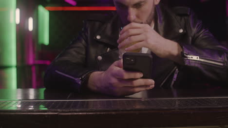 Close-Up-Of-A-Bearded-Man-Using-Mobile-Phone-And-Drinking-While-Sitting-At-Bar-Counter