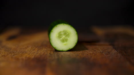 Side-view-of-a-male-hand-chopping-up-a-fresh-cucumber-on-a-wooden-cutting-board