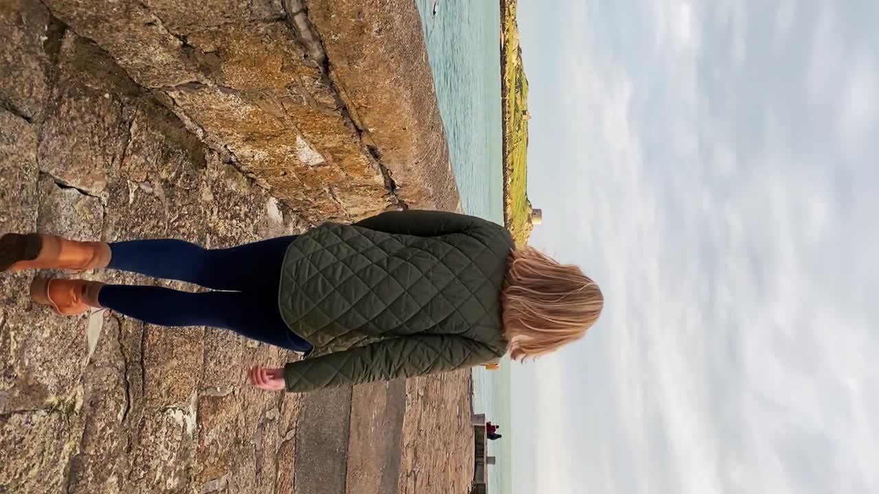 seguimiento detrás de una mujer caminando por el muro del puerto en irlanda
