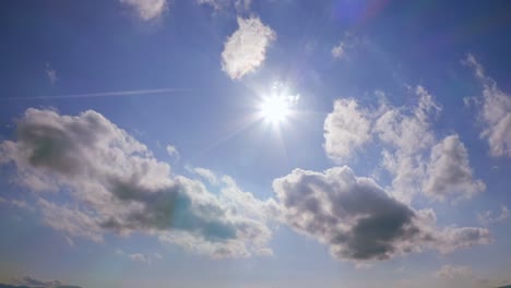 blue sky with idyllic clouds and bright sun, sunrays flare, weather and meteorology, calm and tranquil scene