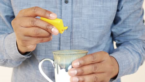 person adding sweetener to a cup
