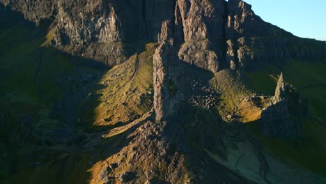 ancient volcanic plug stone spire the old man of storr early morning in winter with pullback reveal of crumbling stone cliffs of the storr, isle of skye, western highlands, scotland, uk