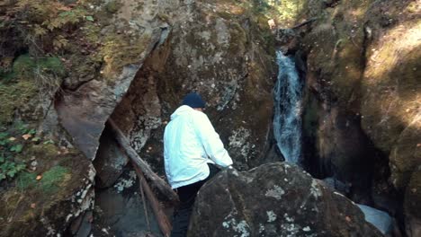 person looking at a waterfall in a rocky forest