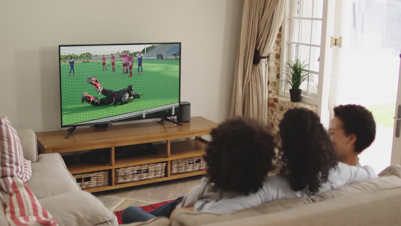 Famiglia felice seduta a casa insieme che guarda una partita di hockey in TV