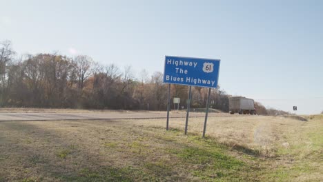 Highway-61,-Das-Blues-Highway-Schild-Am-Straßenrand-In-Mississippi-Mit-Vorbeifahrenden-Fahrzeugen-Und-Einem-Stabilen-Weitwinkelvideo