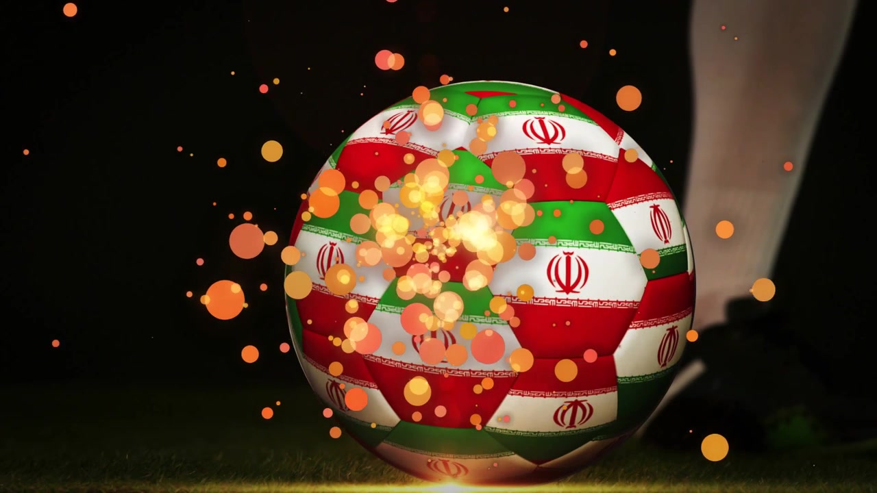 Tacchetti di un giocatore che si muovono verso un pallone da calcio su un campo notturno, con particelle arancioni che si espandono a seguito del calcio