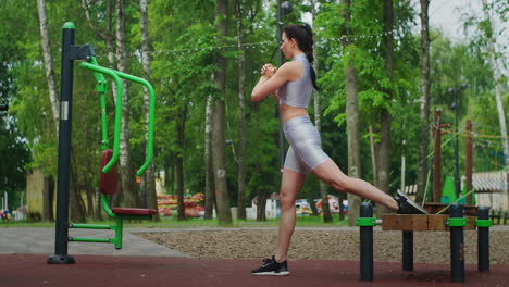 Trenes-De-Atletismo-En-El-Parque-En-Un-Banco-Realizando-Sentadillas-Con-Estocadas-Sobre-Un-Joven