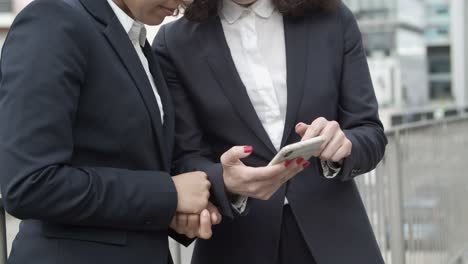 mujeres de negocios serias que usan teléfonos inteligentes en la calle