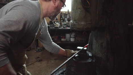 blacksmith using power hammer in workshop