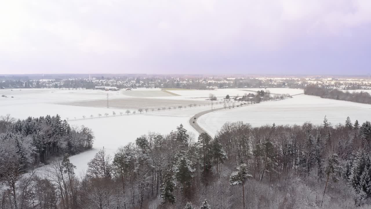 연한 보라색 일몰 하늘 아래 자동차를 운전하는 눈 덮인 풍경