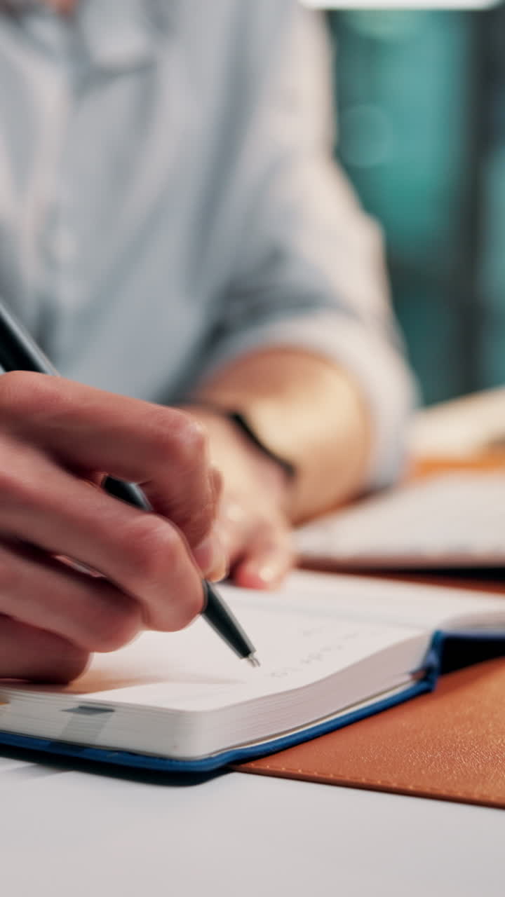 Close-up of Hand Writing in Notebook with Pen