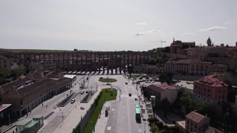 aerial view circling across the aqueduct of segovia, avenue via roma and padre claret spanish old town skyline