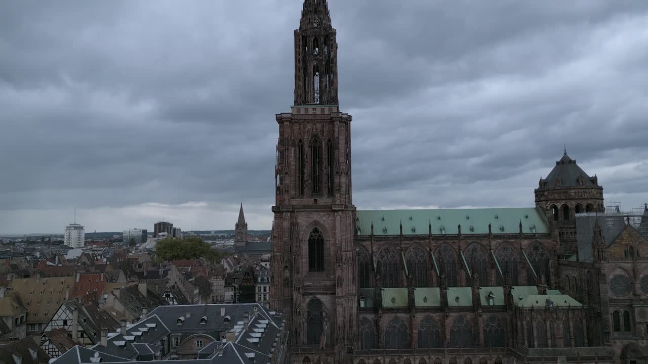 Ripresa aerea diurna suggestiva dell'intricata facciata gotica e del tetto in rame verde della Cattedrale di Strasburgo sotto cieli nuvolosi e drammatici