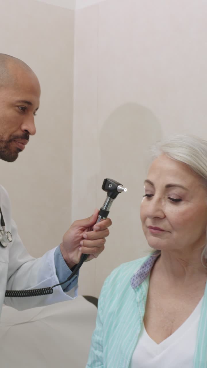 Doctor examining senior patient's ear