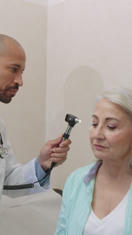 doctor examining senior patient's ear