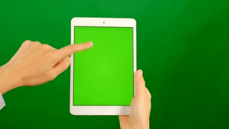 mujer de negocios usando una tableta de pantalla verde en blanco sobre un fondo verde.