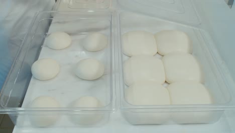 chef showcase two storage tray of pizza dough before and after overnight fermentation