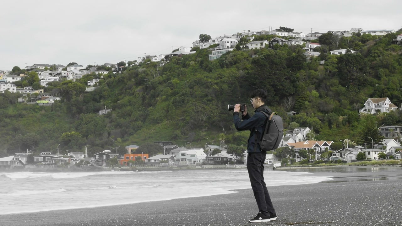 Malaysian Photographer Taking Photos Of Lyall Bay From Shore In Wellington, New Zealand. wide shot