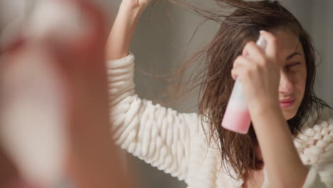 woman applying hairspray to wet hair in the bathroom