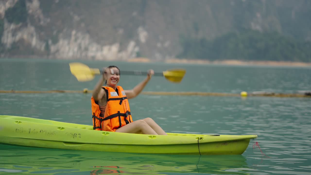 Woman kayaking on a calm lake with mountains in the background