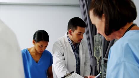 doctors examining senior patient in ward