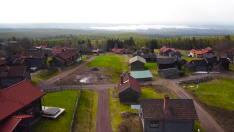 gorgeous aerial drone footage gliding and flying over and above a small cute sweden village or housing area in the middle of a large green and vibrant pine forest with a large lake visible in the back