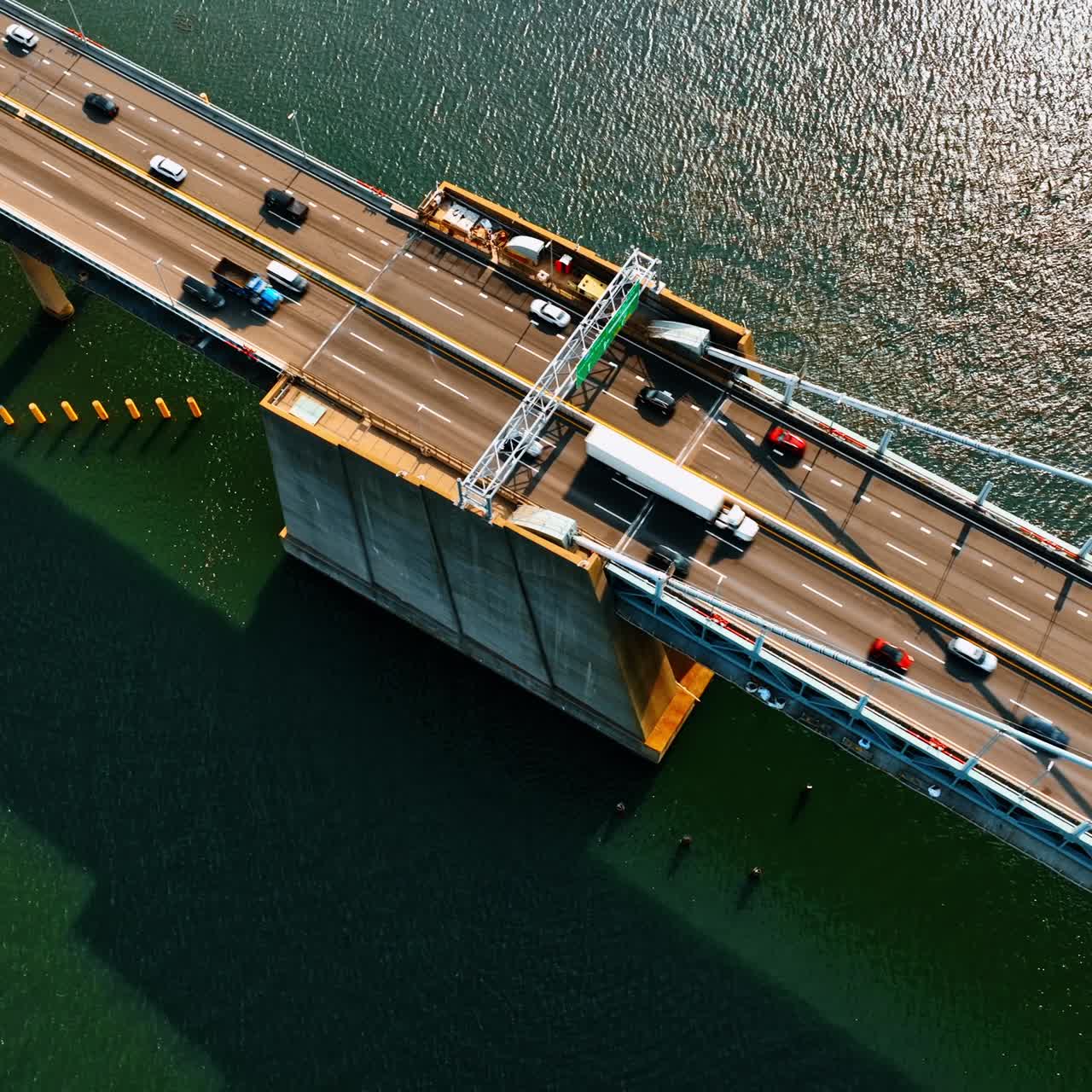 Footage above the bridge over the deep river. Suspension bridge with roads for transport traffic. Top view on sunny day