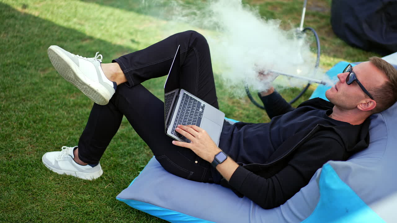 Man Relaxing Outdoors with Laptop and Hookah