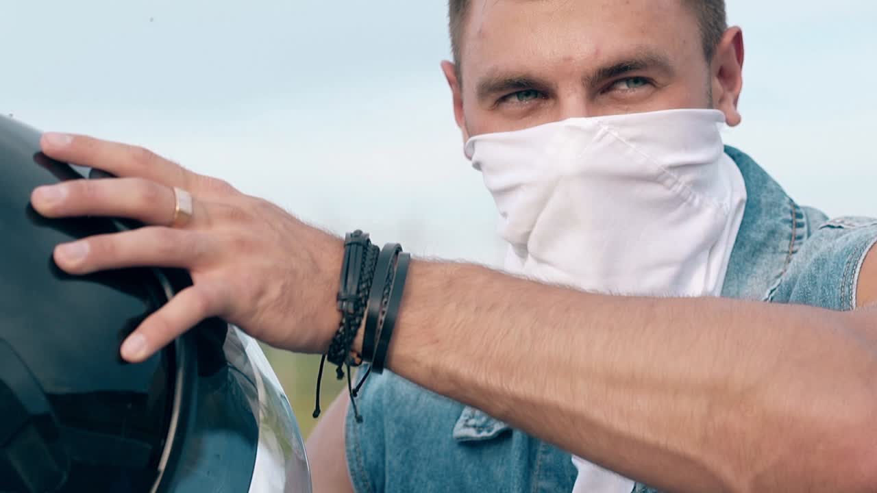 nahaufnahme mann in jeansweste zieht helm und schleuder ab