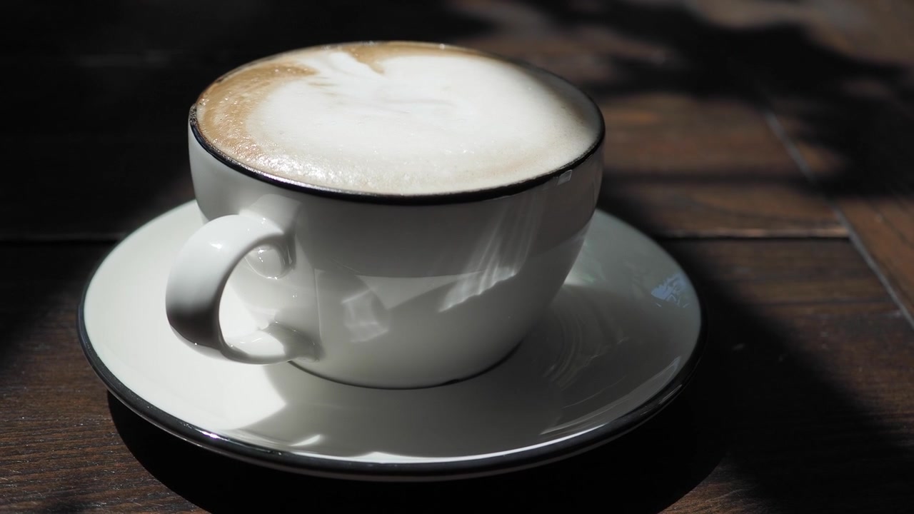 Tazza di caffè bianca con latte art su un tavolo di legno