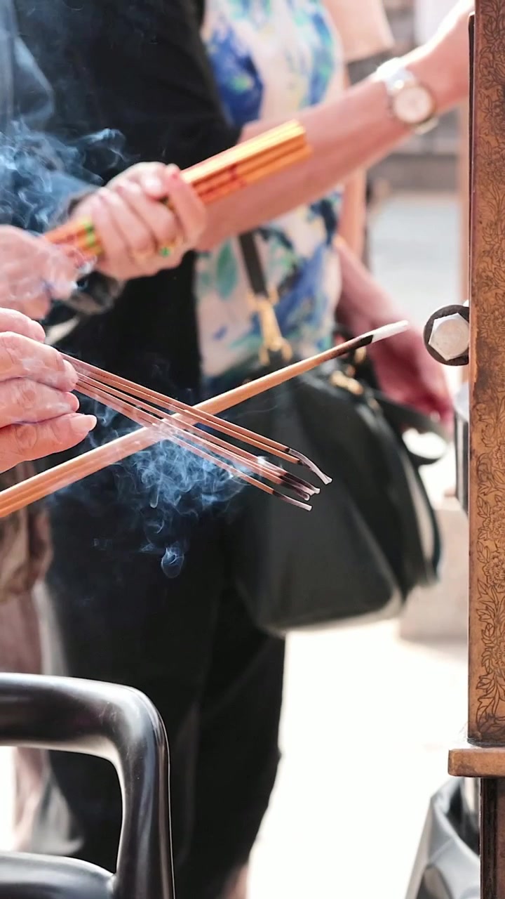 神社で線香に火をつける人々