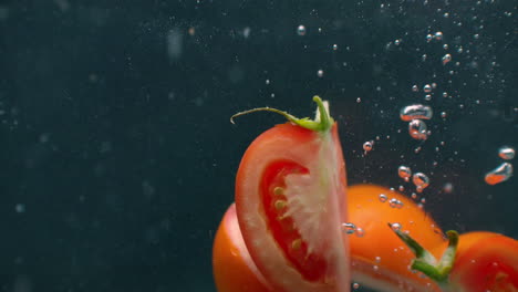 Rodajas-De-Tomate-Maduro-Bajo-El-Agua-Con-Burbujas-De-Aire-Y-En-Cámara-Lenta.-Producto-Vegetariano-Saludable,-Fresco-Y-Jugoso.-Ingredientes-De-Ensalada