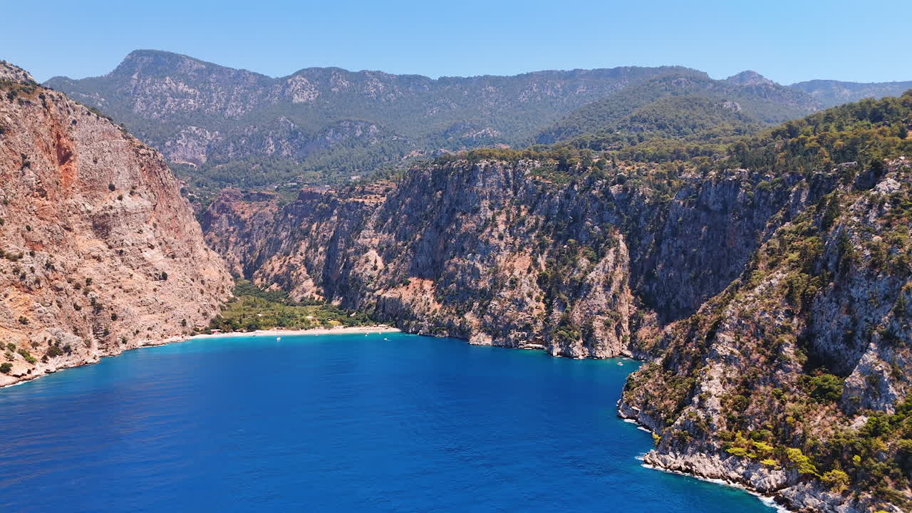 Coastal view of serene turquoise bay. A turquoise bay between rugged cliffs under a blue sky, showcasing nature's beauty in a tranquil setting