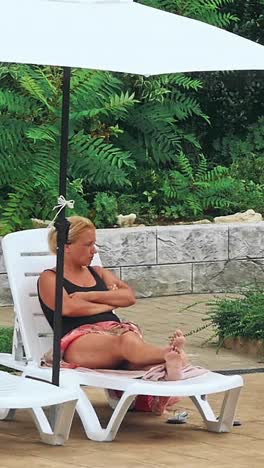 personas sentadas a la orilla de la piscina de un resort durante las vacaciones de verano