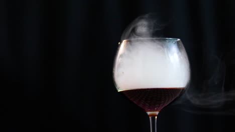 vaso lleno de cola y humo de cerca sobre un fondo negro