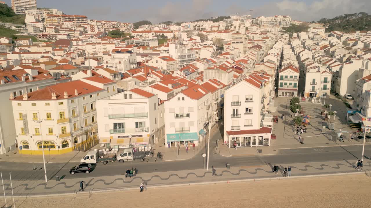 Auto che guidano sulla strada lungo il villaggio sul lungomare a Nazaré, Portogallo