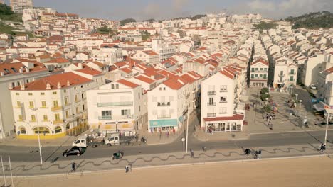 cars driving in the road along the beachfront village in nazare, portugal