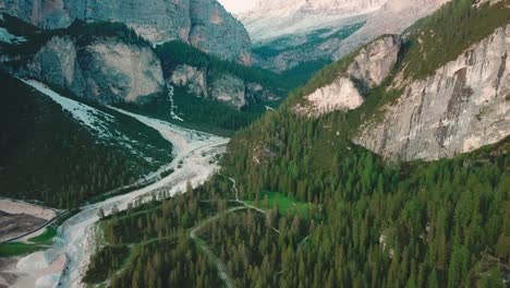 Forward-aerial-shot-in-the-Alps-of-a-valley-next-to-rocky-cliffs