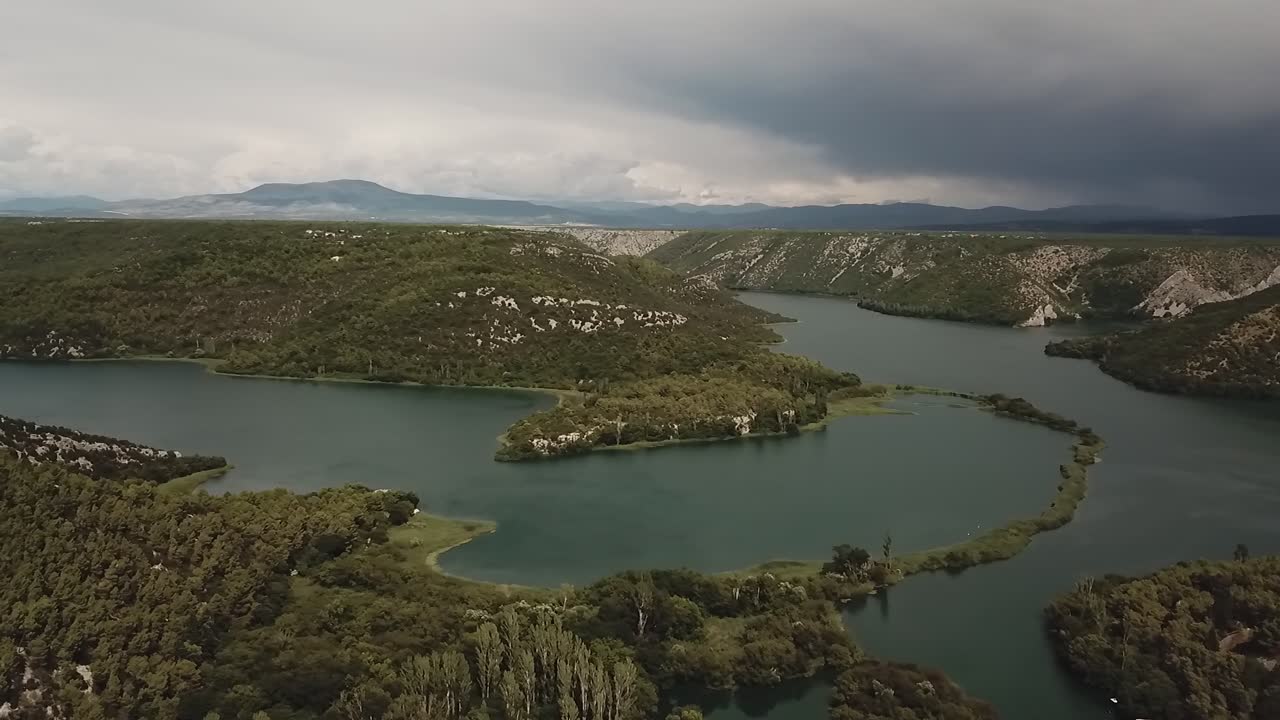 Hırvatistan'ın engebeli dağlarını, vadilerden kıvrılarak akan büyük bir nehri yakalayan drone çekimi, akan su ile kayalık alpin arazi arasındaki zıtlığı vurguluyor.